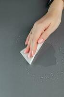 Frau Hand Reinigung das Tabelle Oberfläche mit nass wischt. foto