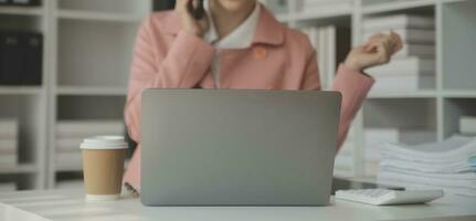 attraktiv lächelnd jung asiatisch Geschäft Frau Arbeit beim Zuhause Büro, asiatisch Frau Arbeiten auf Laptop Computer halten Tablette. foto