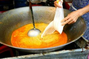 Kochen Essen gießen das Kokosnuss Milch in das golden Orange Curry im das schwenken . foto