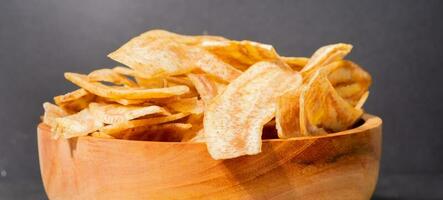 Banane Chips mit ein Süss und salzig Geschmack gemacht von gebraten roh Bananen im ein hölzern Schüssel. traditionell Snacks foto