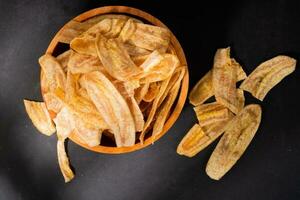 Banane Chips mit ein Süss und salzig Geschmack gemacht von gebraten roh Bananen im ein hölzern Schüssel. traditionell Snacks foto