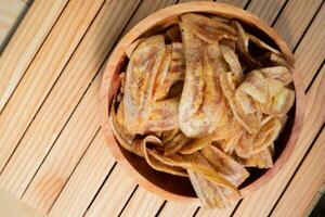 Banane Chips mit ein Süss und salzig Geschmack gemacht von gebraten roh Bananen im ein hölzern Schüssel. traditionell Snacks foto