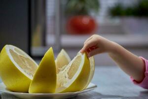 Junge Kleinkind nimmt mit seine Hand Essen Wassermelone Sitzung beim das Küche Tabelle foto