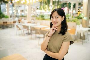 lächelnd schön asiatisch Frau Stehen im Cafeteria beim Einkaufen Einkaufszentrum. foto