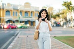 Porträt schön asiatisch Frau Reisender mit Kamera erkunden Straße auf Sommer- Ferien im Bangkok, Thailand foto