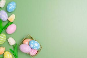 glücklich Ostern Urlaub Gruß Karte Design Konzept. bunt Ostern Eier und Frühling Blumen auf Pastell- Grün Hintergrund. eben legen, oben Sicht, Kopieren Raum. foto