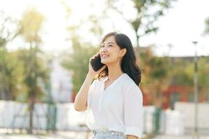 Porträt schön jung asiatisch Frau mit Clever Handy, Mobiltelefon Telefon um draussen Natur Aussicht im ein sonnig Sommer- Tag foto