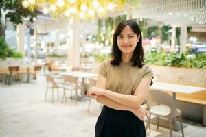 lächelnd schön asiatisch Frau Stehen im Cafeteria beim Einkaufen Einkaufszentrum. foto