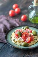 Pasta mit Tomate Soße, Oliven und Kapern auf das Teller foto