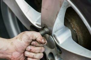 Auto Rad Ersatz. Selbstbedienung Reifen passend zu Konzept. mit ein Rad Schlüssel zu Twist das Rad Nüsse. foto