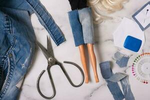 Nähen Puppe Kleider von getragen Denim kurze Hose. Wiederverwendung Ding, Recycling Konzept foto