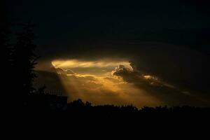 dunkel dicht Himmel und Strahlen von warm Orange Licht bekommen aus von das Wolken foto