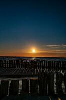 bunt Sonnenuntergang Über das Polieren baltisch Meer mit dunkel Himmel Wolken und Wellenbrecher foto