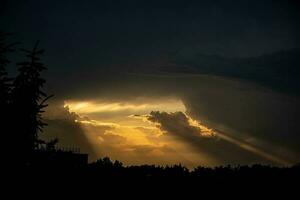 dunkel dicht Himmel und Strahlen von warm Orange Licht bekommen aus von das Wolken foto