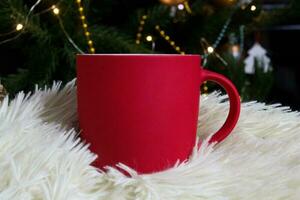 leer rot Becher mit Weihnachten Baum auf Hintergrund, Matte Tee oder Kaffee Tasse mit Weihnachten und Neu Jahr Dekoration, horizontal spotten oben mit Keramik Becher zum heiß Getränke, leer Geschenk drucken Vorlage foto