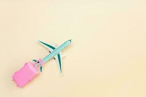 Spielzeug Flugzeug trägt ein Koffer auf ein Licht Hintergrund mit Kopieren Raum, Reise Inhalt foto