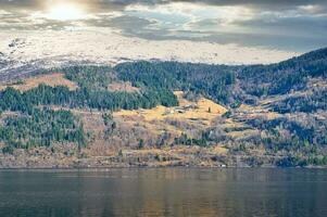 Fjord mit Schnee bedeckt Berge auf Horizont und dramatisch Himmel. das Wasser im Norwegen foto