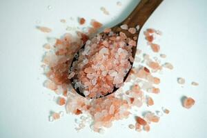 Himalaya Rosa Salz- Kristalle im ein hölzern Löffel auf Weiß Hintergrund. foto