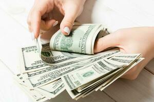 Geschäftsfrau Hände Zählen einer hundert Dollar Rechnungen auf hölzern Hintergrund. Gehalt und Lohn Konzept. oben Aussicht von Investition Konzept foto