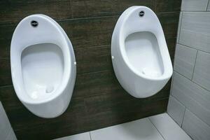 Weiß Urinale im das Herren Toilette von das Einkaufen Center foto
