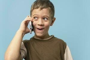 heiter frech kaukasisch Junge reden auf das Telefon . ein charmant Kind mit ein Telefon foto