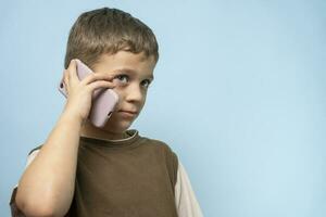 frech kaukasisch Junge reden auf das Telefon . ein charmant Kind mit ein Telefon foto