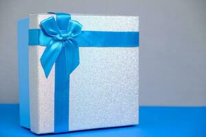 Geschenk Box Blau Hintergrund ist gebunden mit grau Band mit Bogen. foto