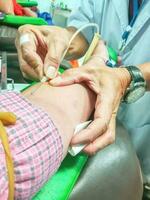 Hände von Arzt Verwendet allmählich erstechen medizinisch Nadel und iv Katheter auf Blut Spender Arm im Blut Spende Zimmer. foto
