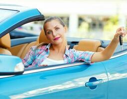 jung ziemlich Frau Sitzung im ein Cabrio Auto mit das Schlüssel im Hand foto