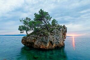 das Symbol von Brela, das brela Stein während Sonnenuntergang. diese Felsen im das Meer, bewachsen mit Kiefern, zeigt an das Stärke und Leistung von Überleben und Wachstum von das Stein selbst. natürlich Schönheit. foto