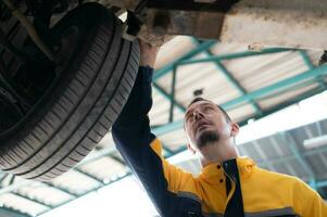 Auto Reparatur Mechaniker das Fahrwerk von das Auto ist Sein inspiziert zum Beschädigung verursacht durch schwer Kollisionen. foto