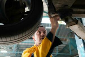 Auto Reparatur Mechaniker das Fahrwerk von das Auto ist Sein inspiziert zum Beschädigung verursacht durch schwer Kollisionen. foto