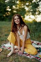jung schön Hippie Frau Sitzung auf das Boden im Natur im das Herbst im Öko Kleidung im das Sonnenuntergang Licht, ein Lebensstil von Reise und Harmonie mit das Welt foto