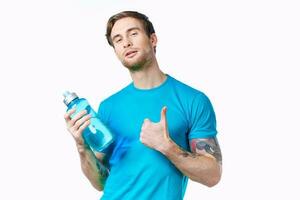 Athlet im ein Blau T-Shirt mit ein Flasche von Wasser auf ein Weiß Hintergrund und ein tätowieren auf seine Arm foto