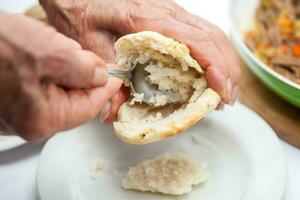 ausgestopft kolumbianisch Arepa Vorbereitung. Nahansicht von Frau Hände Zerkleinern Rindfleisch foto