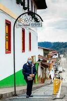 Salento, Kolumbien - - Juli 2021. Senior Frau tragen ein Gesicht Maske beim ein traditionell bunt Straße im das schön kolonial Stadt, Dorf von Salento im das Region von quindio im Kolumbien foto