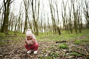 Baby Mädchen spielen mit Stöcke im Frühling Wald. foto