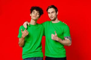 zwei Männer umarmen im Grün T-Shirts auf ein rot Hintergrund foto
