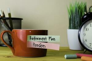 Pensionierung planen und die Pension. Handschrift auf klebrig Anmerkungen im Kleider Heringe auf hölzern Büro Schreibtisch foto