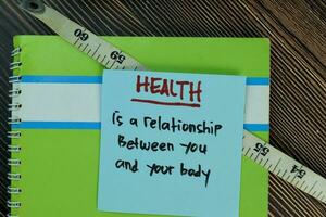 Gesundheit ist ein Beziehung zwischen Sie und Ihre Körper schreiben auf klebrig Anmerkungen isoliert auf hölzern Tisch. Motivation Konzept foto
