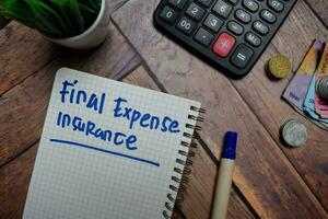 finanziell Kosten Versicherung schreiben auf ein Buch isoliert auf hölzern Tisch. foto