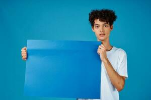 heiter Kerl mit lockig Haar und Blau Attrappe, Lehrmodell, Simulation Poster Werbung foto