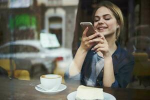 Frau mit Telefon im Hände chatten Frühstück im ein Cafe foto