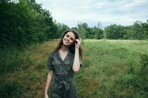 Frau im das Feld Grün Overall Lächeln richtet sich auf Haar Grün Bäume foto