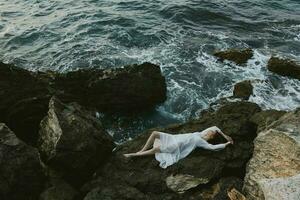 Frau im ein Weiß Kleid Lügen auf ein Stein im ein Weiß Kleid Natur Landschaft foto