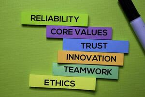 Zuverlässigkeit, Ader Werte, Vertrauen, Innovation, Zusammenarbeit, Ethik Text auf klebrig Anmerkungen isoliert auf Grün Schreibtisch. Mechanismus Strategie Konzept foto