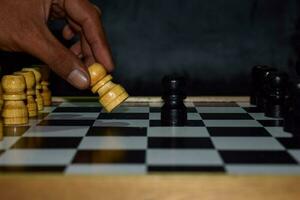 Hand von Geschäftsmann ziehen um Schach Zahl im Wettbewerb Erfolg spielen. Strategie, Verwaltung oder Führung Konzept auf ein hölzern Tabelle foto