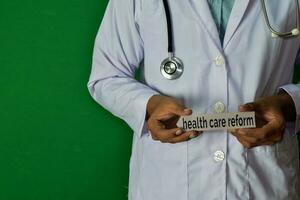 Arzt Stehen auf Grün Hintergrund. halt das Gesundheit Pflege Reform Papier Text. medizinisch und Gesundheitswesen Konzept. foto