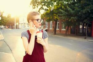 ziemlich Frau mit Brille auf das Straße reden auf das Telefon im Sommer- foto