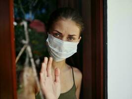 Frau im medizinisch Maske suchen aus das Fenster traurig aussehen Nahansicht foto